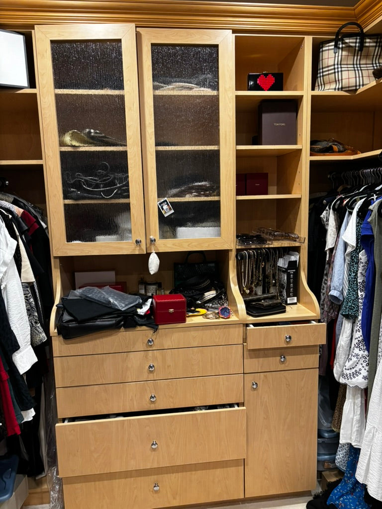 Closet with wooden wardrobe and shelves filled with clothes and items.