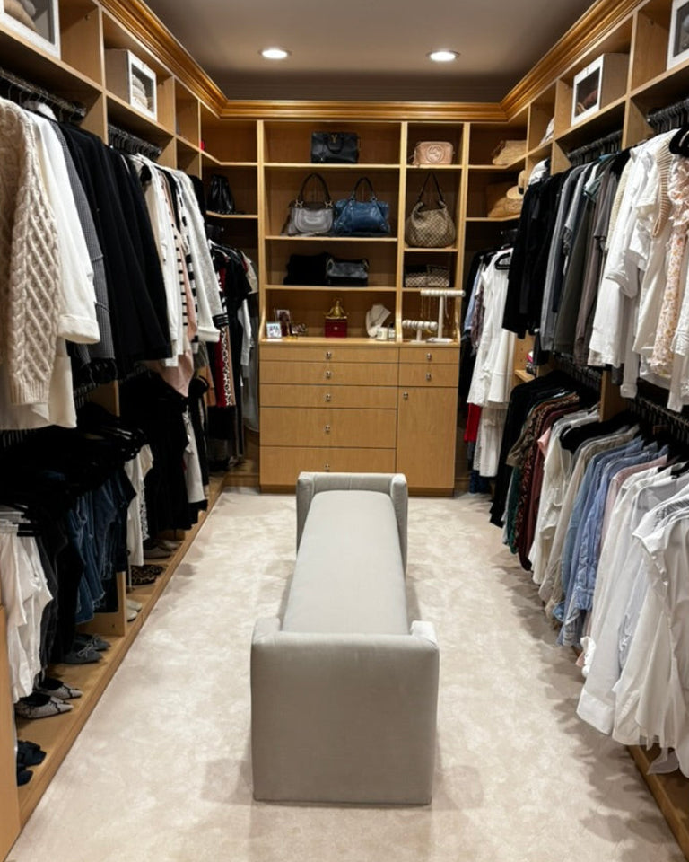 Alyssa Lane - Wardrobe Refinement: 
Large walk-in closet with wooden shelves and clothing racks, featuring a gray bench in the center.