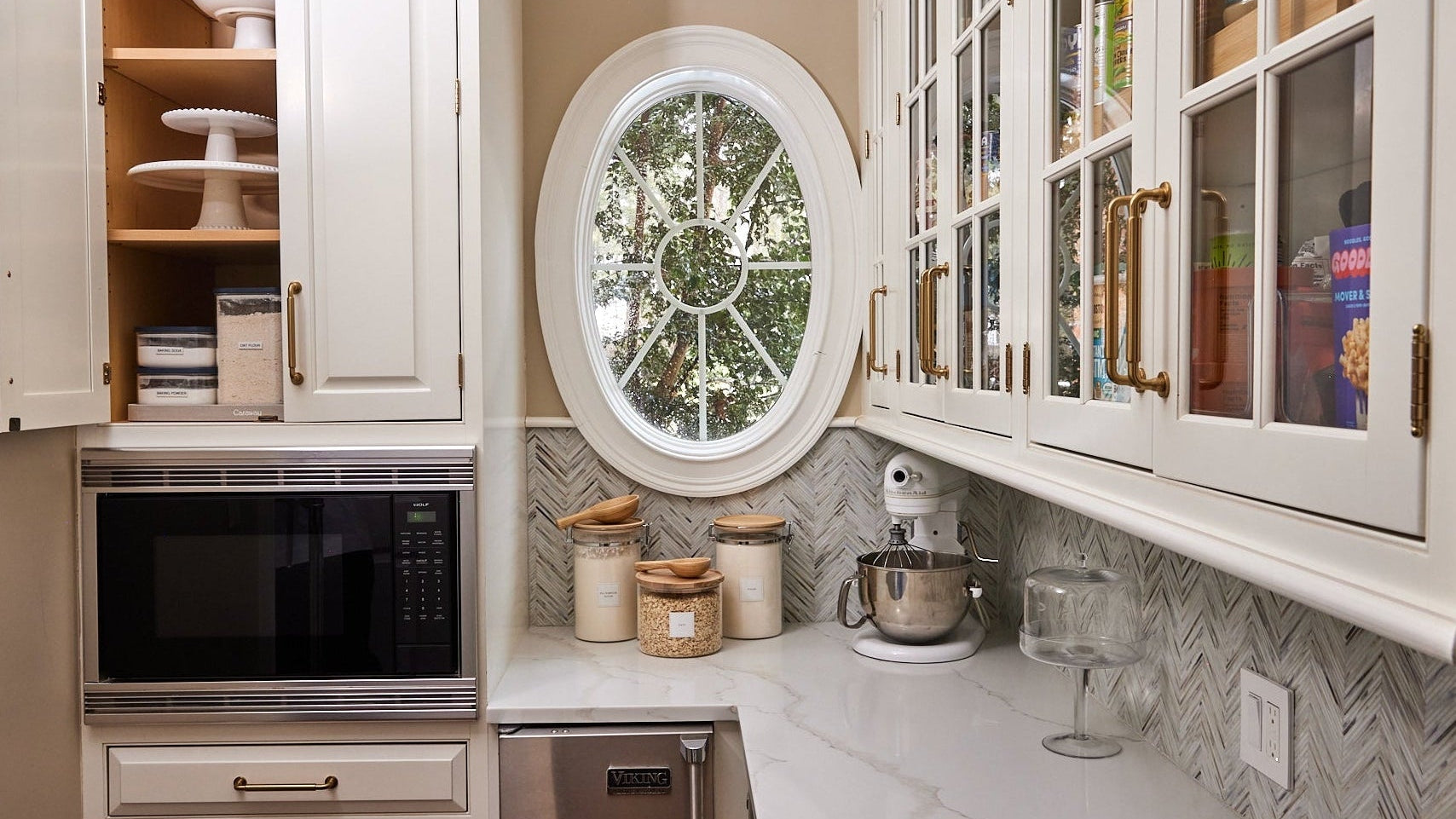 Kitchen corner with white cabinets, round window, and various kitchen items.