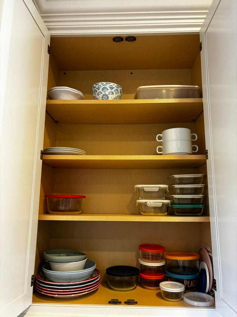 Shelved cabinet with various kitchenware including bowls, plates, and containers.
