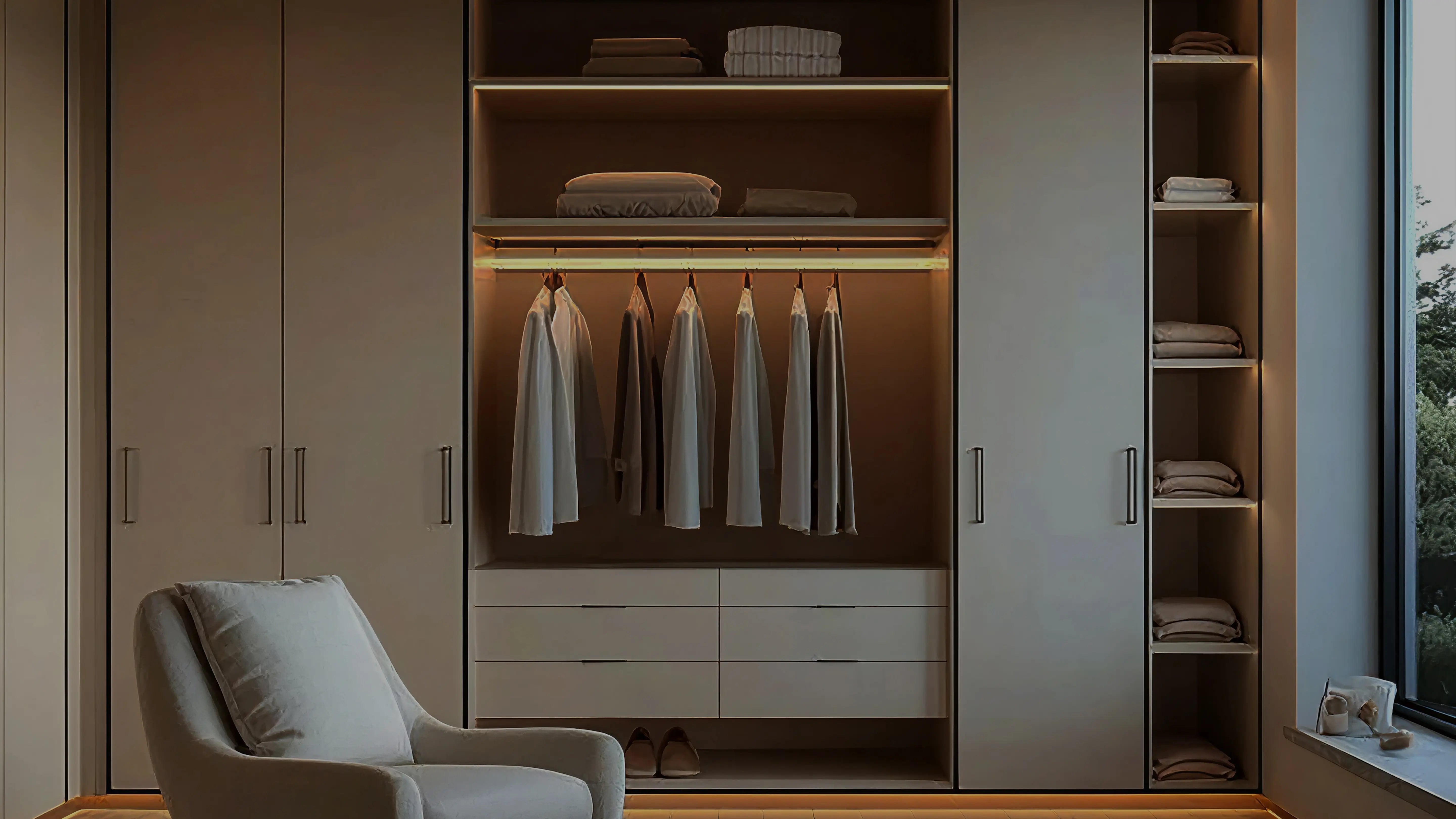 Modern wardrobe with clothes hanging and shelves in a well-lit room.