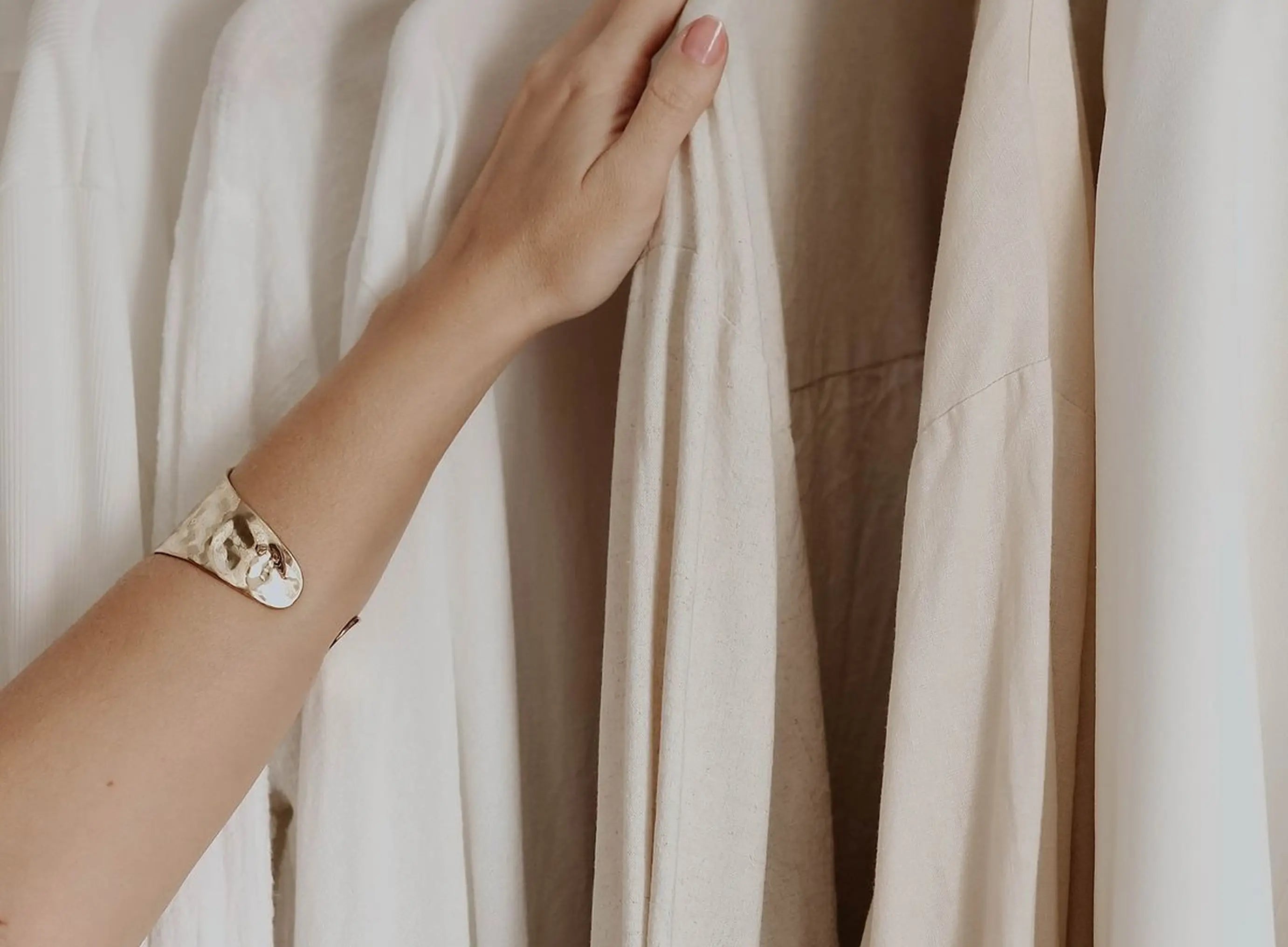 Hand with a gold bracelet touching a white shirts