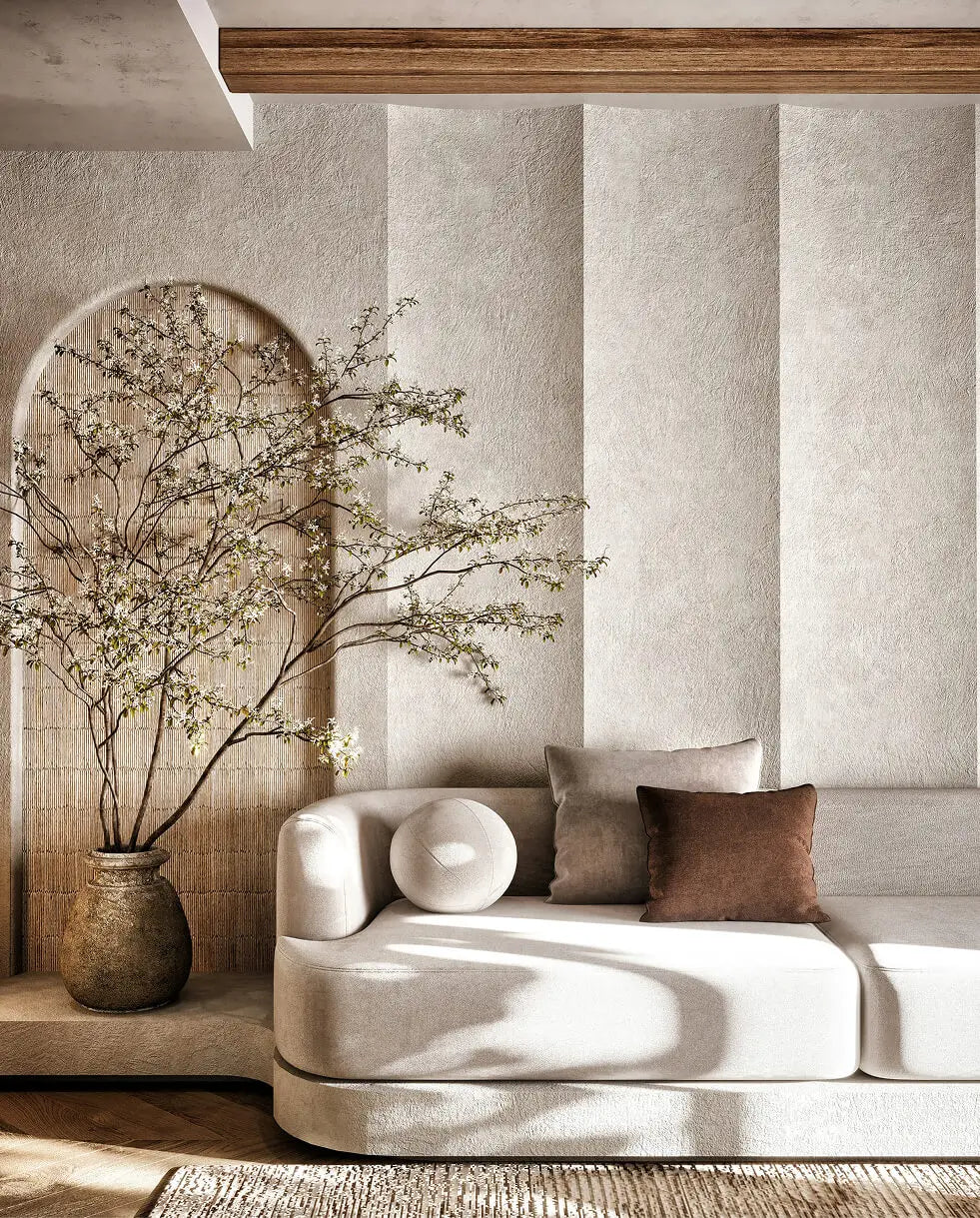 Modern living room with a sofa, decorative pillows, and a vase with branches.