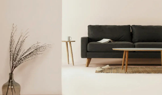 Modern living room with a black sofa, coffee table, and decorative elements.